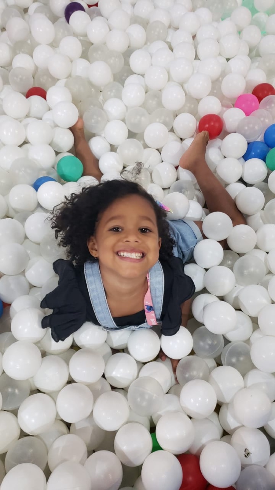 Criança sorrindo na piscina de bolinhas da Dias do Saber